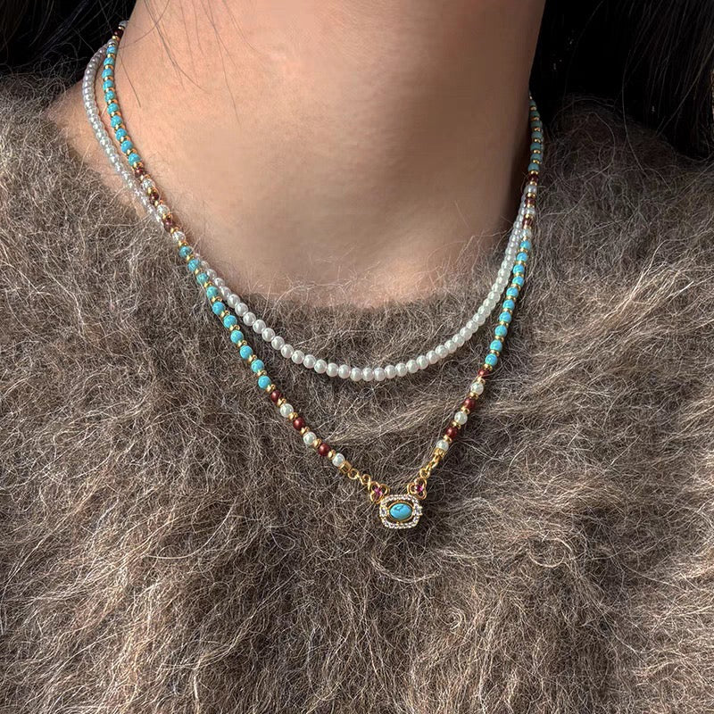 Model wearing Vintage Halo Turquoise and Pearl Necklace layered over grey sweater