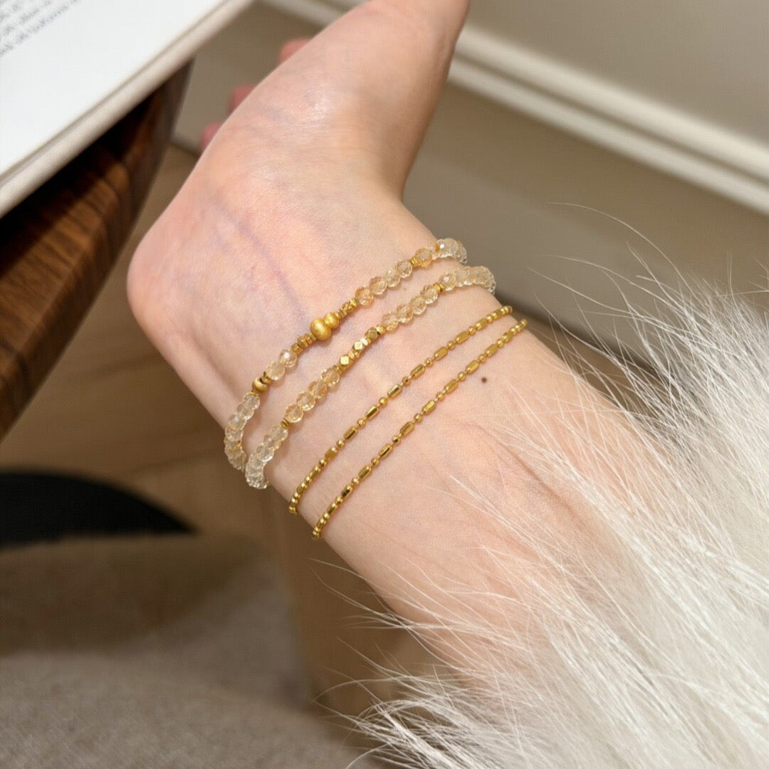 Woman wearing natural faceted citrine double wrap bracelet stacked with delicate gold chains