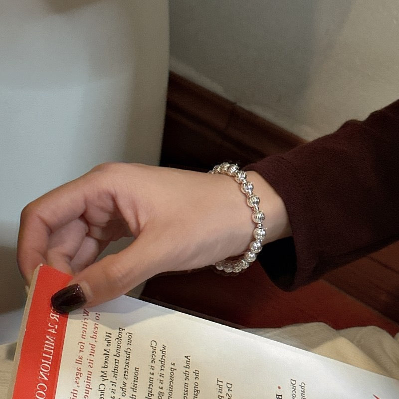 Model reading a book wearing S925 Diamond-Cut Bead Bracelet