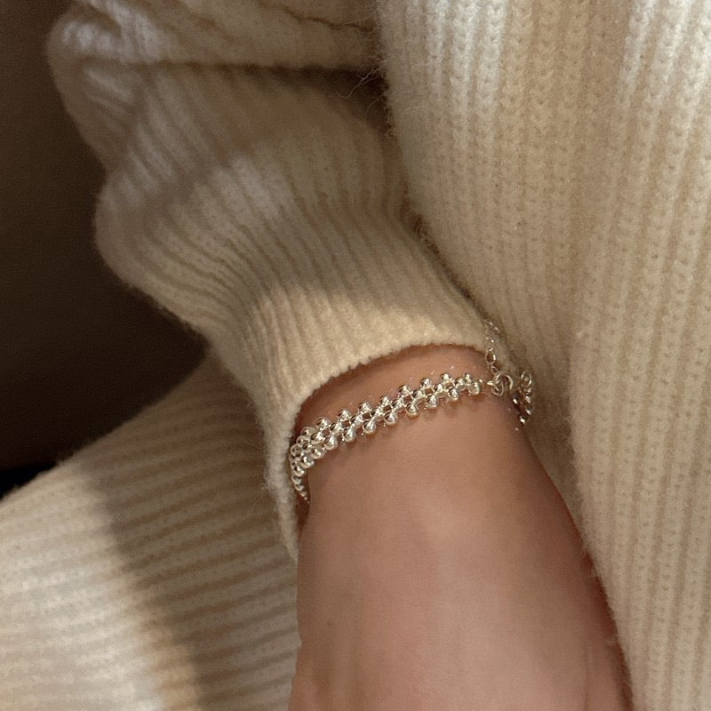 Close-up of matching woven silver bead ring on hand