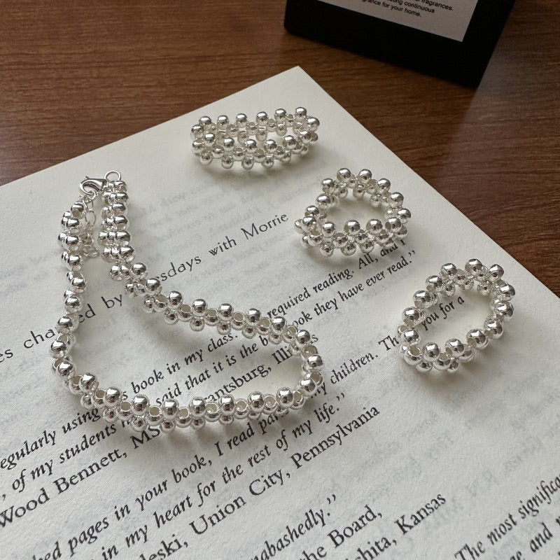 Model wearing S925 sterling silver triple-row woven bead bracelet and matching ring with cream knit sweater
