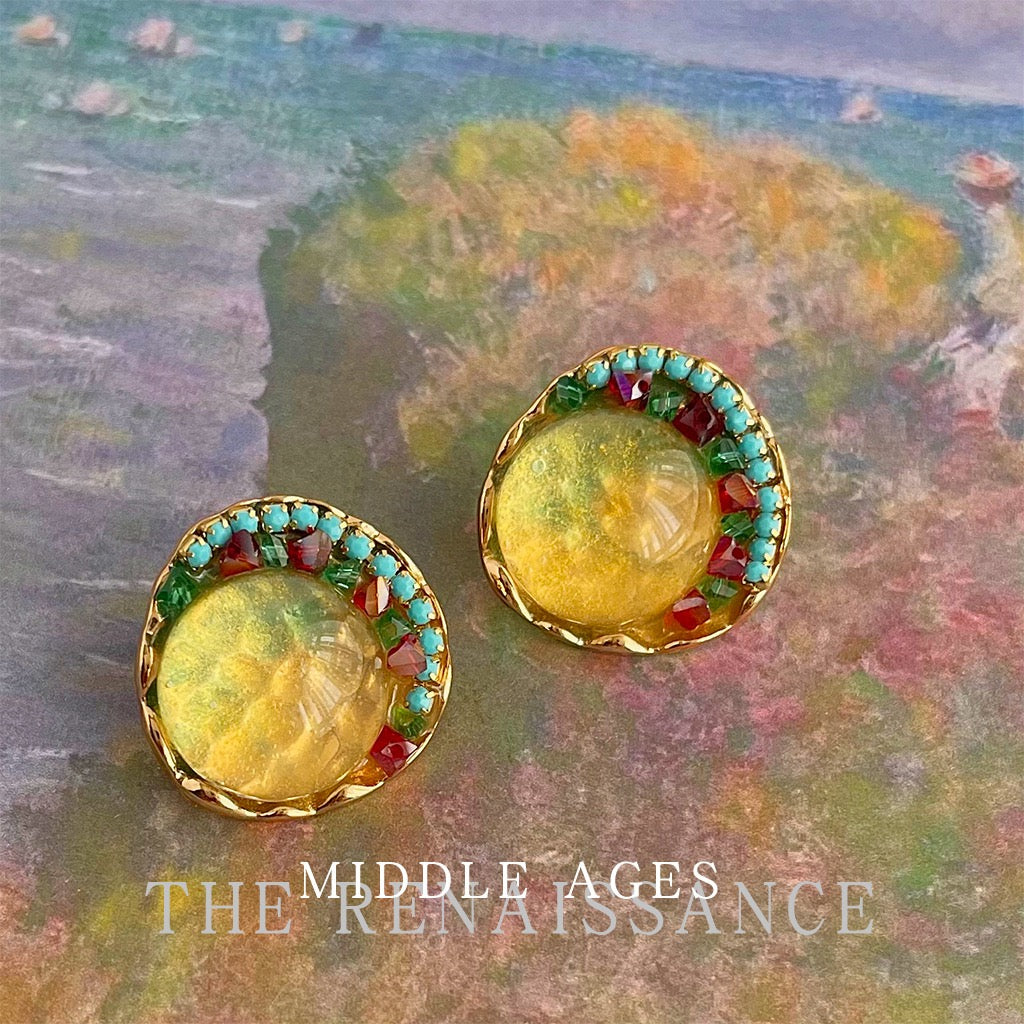 Artistic flat lay of vintage French amber glass earrings on floral painting