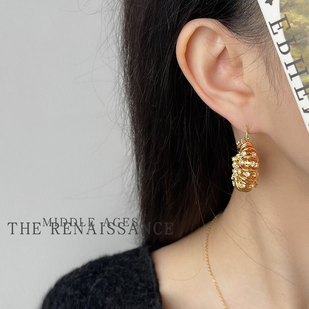 Model wearing chunky gold pavé crystal spiral hoop earring