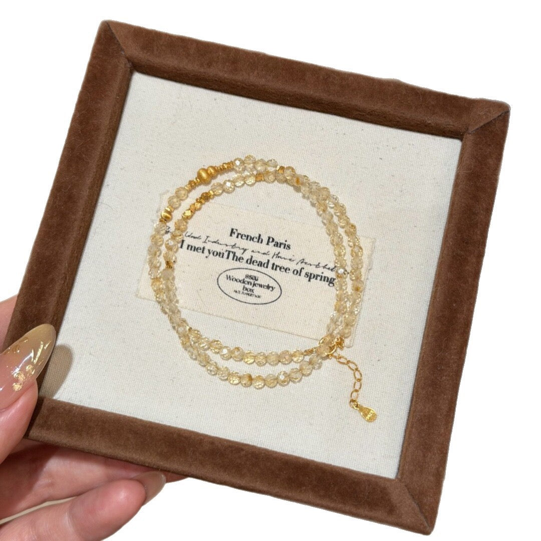 Close-up of faceted citrine crystal bracelet layered with fine gold beaded bracelets
